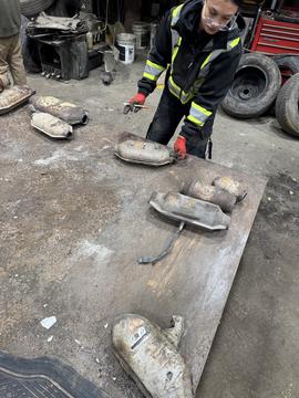 Worker Sorting Catalytic Converters at Scrap Metal Recycling Facility